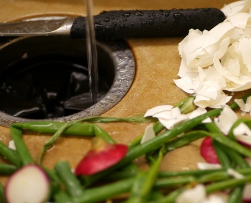 eggshells and vegetable scraps laying next to garbage disposal in kitchen sink