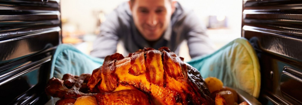 man tending to turkey in oven on thanksgiving