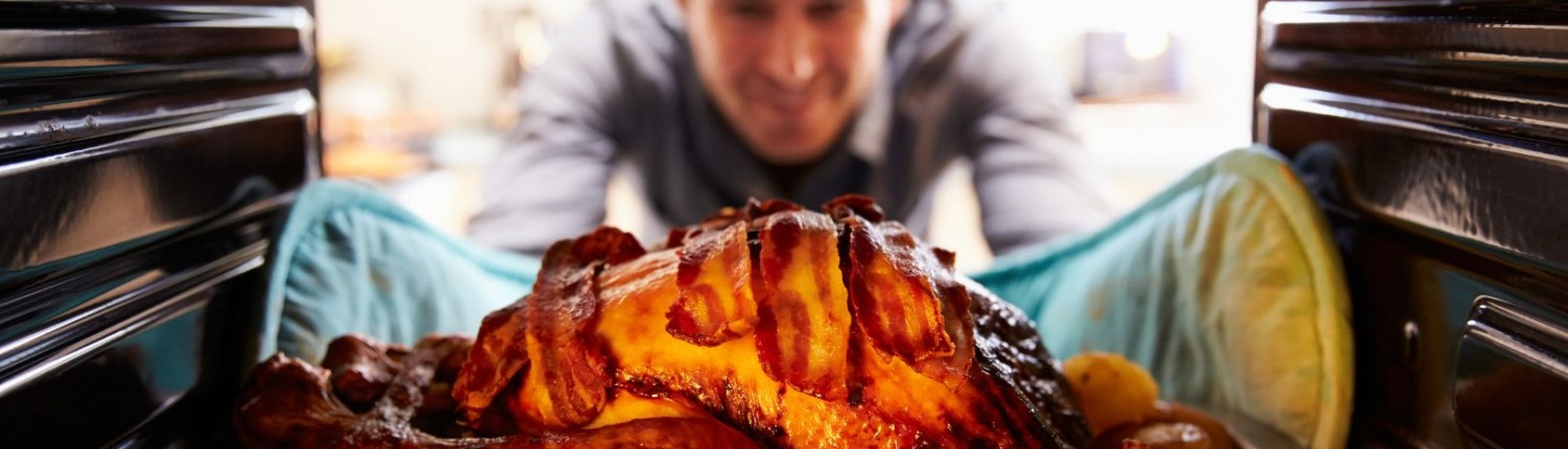 man tending to turkey in oven on thanksgiving