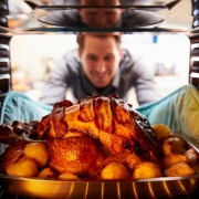 man tending to turkey in oven on thanksgiving