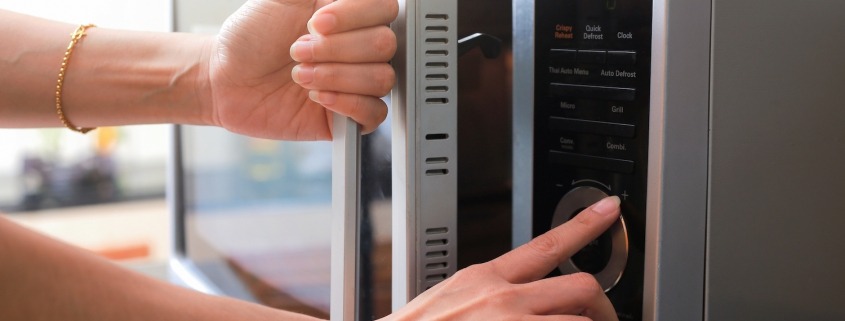 Woman's Hands Closing Microwave Oven Door And Preparing Food in microwave.