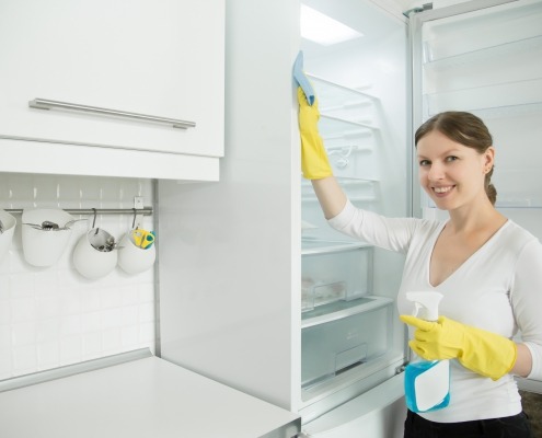 Young smiling woman wearing rubber gloves cleaning the fridge, photo by Yanalya on Freepik.com