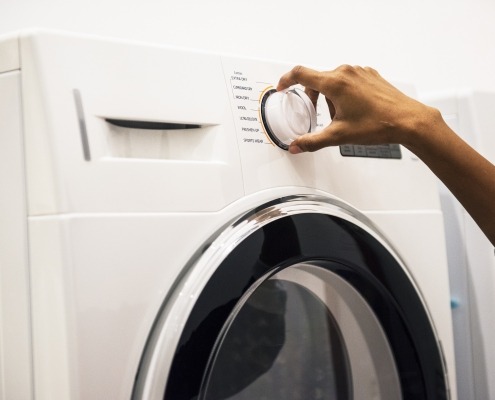 Woman's hand on the dial of a All-In-One Washer Dryer