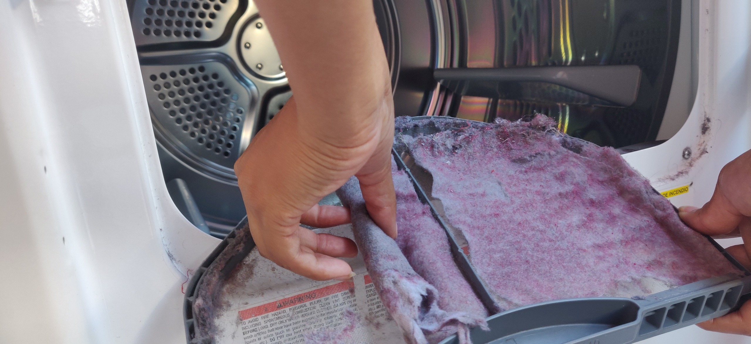 Hand removing lint from the lint filter of a dryer