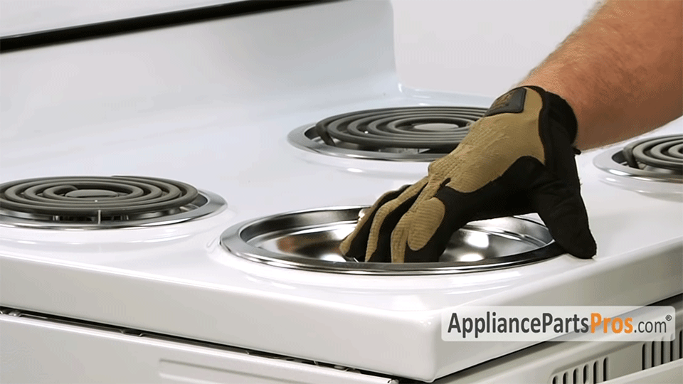 hands removing the drip pan on a stove top