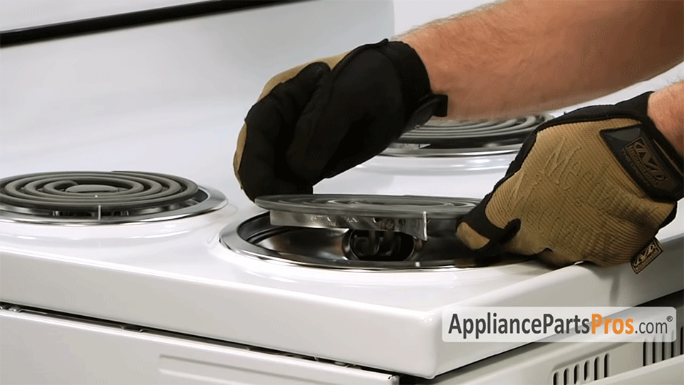 Hands removing a heating element from a stove top