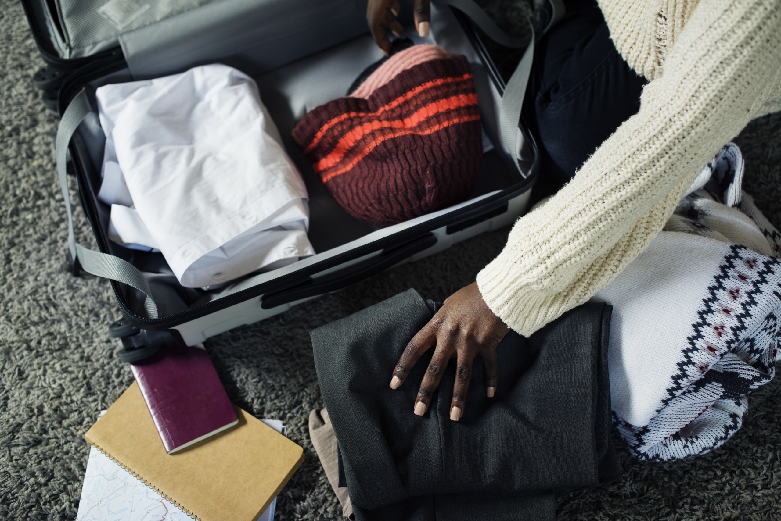 Feminine African American hand packing a suitcase, Image by rawpixel.com on Freepik