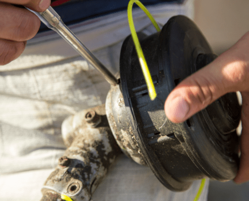 Close up of hands demonstrating how to restring your weed eater