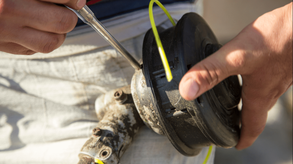 Close up of hands demonstrating how to restring your weed eater