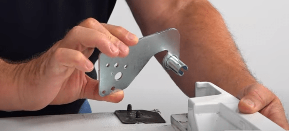 close up of hands replaceing the upper door hinge on a refrigerator