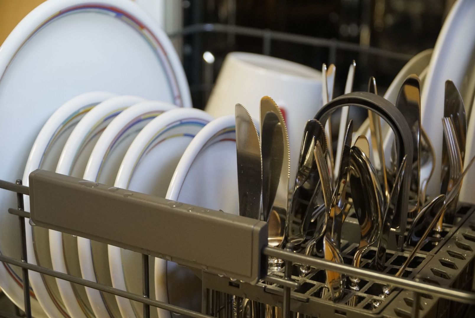 open dishwasher door with a rack full of dishes in kitchen