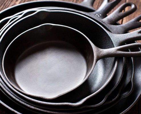season cast iron skillets stacked together on wooden table