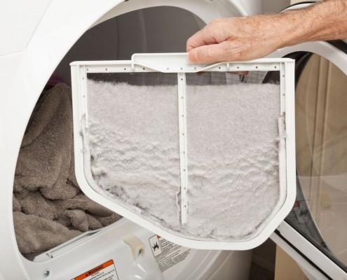 open dryer door with man holding full lint trap