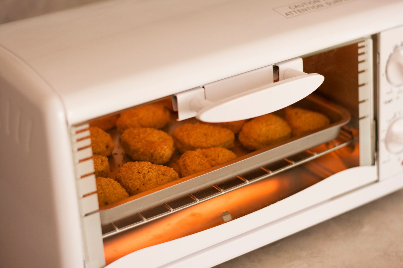 closed toaster oven with breaded meat cooking inside