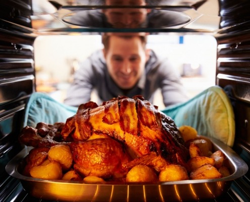 man tending to turkey in oven on thanksgiving